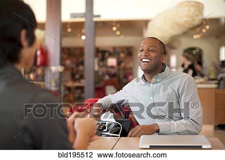 Stock Image - Smiling businessmen talking in cafe. Fotosearch