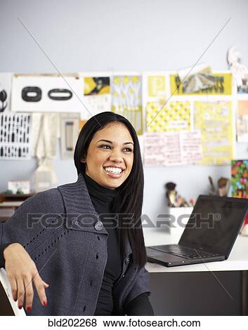 Smiling businesswoman sitting at desk View Large Photo Image Stock Photo - Smiling businesswoman sitting at desk. Fotosearch