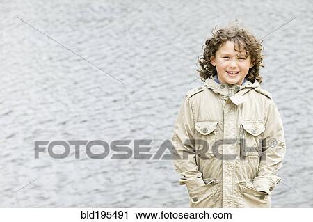 Stock Image - Smiling Caucasian boy with hands in pockets. Fotosearch