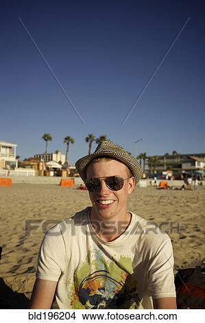 Picture - Smiling Caucasian man sitting on beach. Fotosearch
