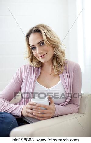 Stock Image - Smiling Caucasian woman drinking coffee. Fotosearch