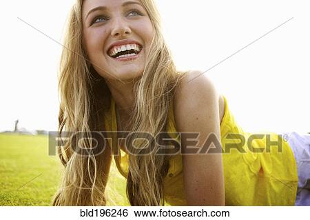 Stock Photograph - Smiling Caucasian woman laying in grass. Fotosearch