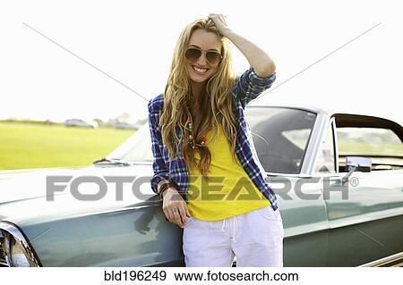Smiling Caucasian woman leaning against car View Large Photo Image Stock Photo - Smiling Caucasian woman leaning against car. Fotosearch