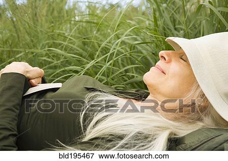 Stock Photo - Smiling Caucasian woman sleeping in grass. Fotosearch