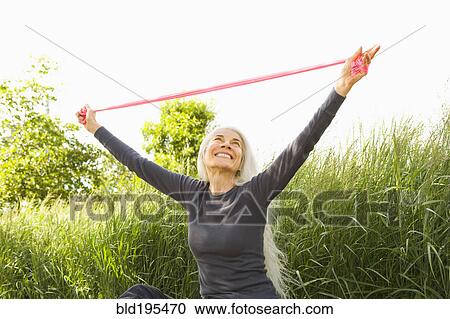 Stock Image - Smiling Caucasian woman stretching with resistance band. Fotosearch