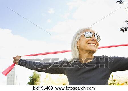 Smiling Caucasian woman stretching with resistance band View Large Photo Image Stock Photo - Smiling Caucasian woman stretching with resistance band. Fotosearch