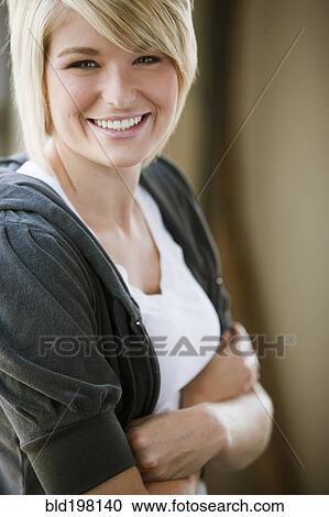 Stock Image - Smiling Caucasian woman with arms crossed. Fotosearch