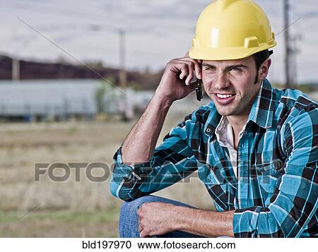 Stock Image - Smiling construction worker talking on cell phone. Fotosearch