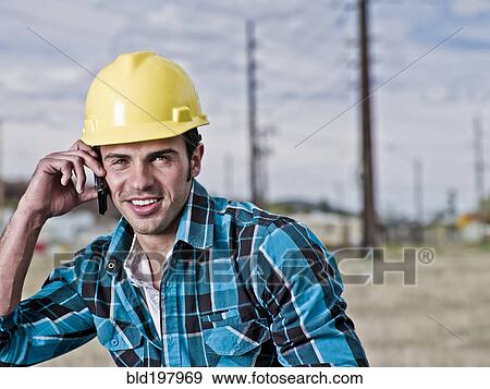 Stock Photo - Smiling construction worker talking on cell phone. Fotosearch