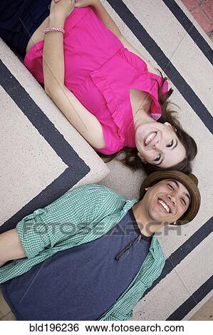 Smiling couple laying on floor together View Large Photo Image Stock Photograph - Smiling couple laying on floor together. Fotosearch