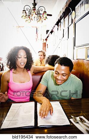 Picture - Smiling couple reading menu in diner. Fotosearch