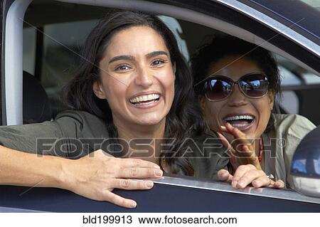 Stock Image - Smiling friends driving in car. Fotosearch