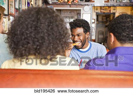 Stock Photograph - Smiling friends eating in diner booth. Fotosearch