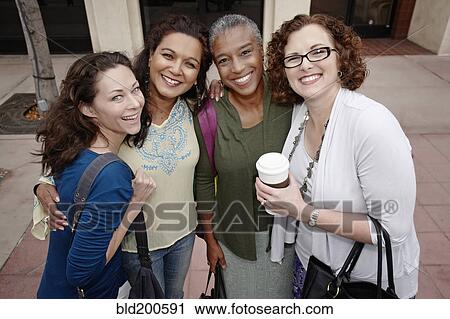 Stock Image - Smiling friends standing on sidewalk. Fotosearch
