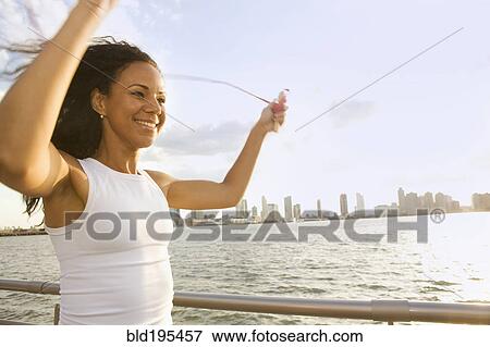 Smiling Hispanic woman jump roping at waterfront View Large Photo Image Stock Photo - Smiling Hispanic woman jump roping at waterfront. Fotosearch