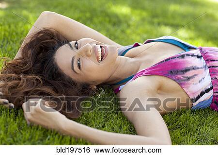Smiling Hispanic woman laying in grass View Large Photo Image Stock Photograph - Smiling Hispanic woman laying in grass. Fotosearch
