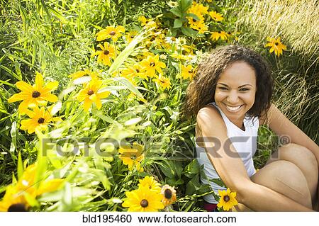 Smiling Hispanic woman sitting in field of flowers View Large Photo Image Stock Image - Smiling Hispanic woman sitting in field of flowers. Fotosearch
