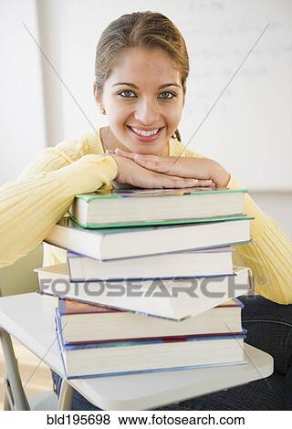 Stock Photo - Smiling Indian student leaning on stack of textbooks. Fotosearch