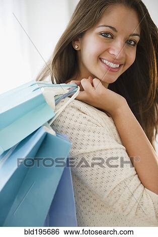 Stock Photograph - Smiling Indian woman carrying shopping bags. Fotosearch