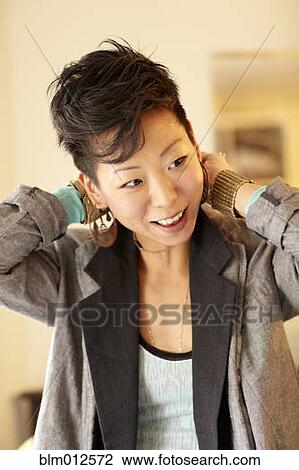 Stock Image - Smiling Korean woman dressing. Fotosearch