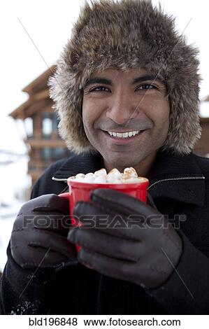 Stock Photo - Smiling man drinking hot chocolate outdoors. Fotosearch