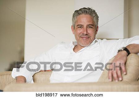 Stock Photo - Smiling man relaxing on sofa. Fotosearch