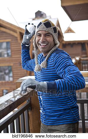 Stock Photograph - Smiling man throwing snowball. Fotosearch