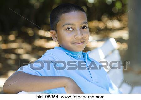 Smiling mixed race boy sitting in park View Large Photo Image Picture - Smiling mixed race boy sitting in park. Fotosearch