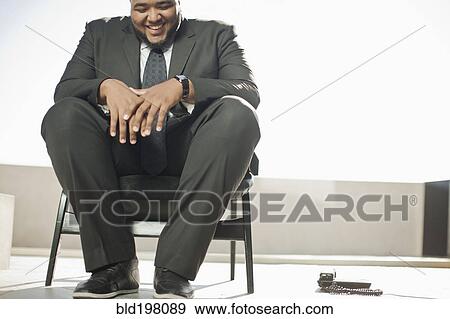 Stock Photo - Smiling mixed race businessman sitting on patio. Fotosearch
