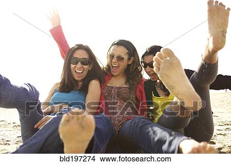 Picture - Smiling mixed race sisters playing on beach. Fotosearch