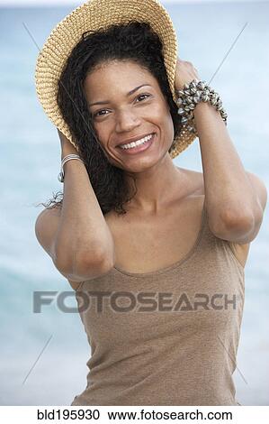 Stock Image - Smiling mixed race woman holding hat. Fotosearch