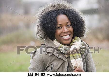 Stock Image - Smiling mixed race woman in fur-hooded coat. Fotosearch
