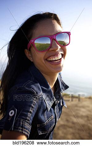 Stock Photo - Smiling mixed race woman laughing on beach. Fotosearch