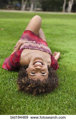 Stock Photo - Smiling mixed race woman laying in grass. Fotosearch
