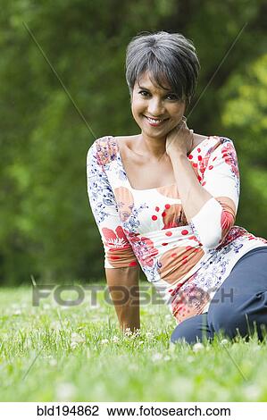 Smiling mixed race woman sitting in field View Large Photo Image Stock Image - Smiling mixed race woman sitting in field. Fotosearch