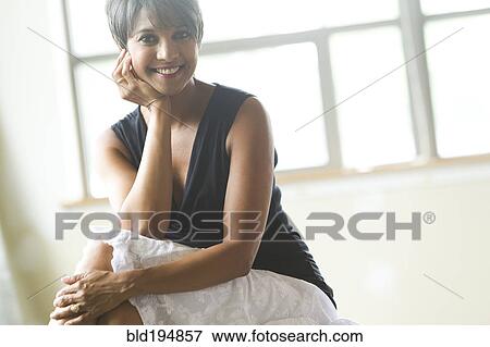 Stock Photo - Smiling mixed race woman sitting. Fotosearch