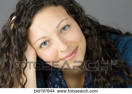 Picture - Smiling mixed race woman with head in hands. Fotosearch