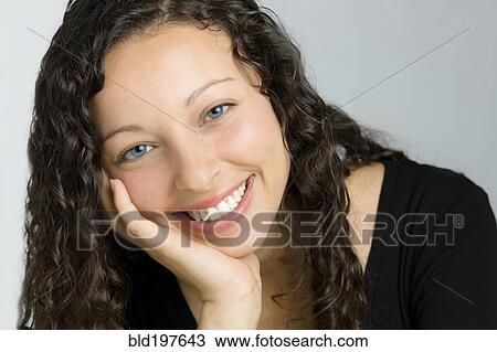 Stock Image - Smiling mixed race woman with head in hands. Fotosearch