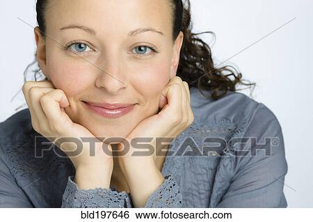 Stock Photograph - Smiling mixed race woman with head in hands. Fotosearch