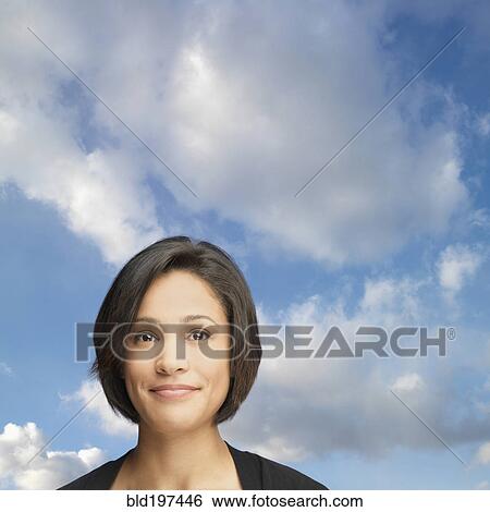 Stock Photograph - Smiling mixed race woman with sky in background. Fotosearch