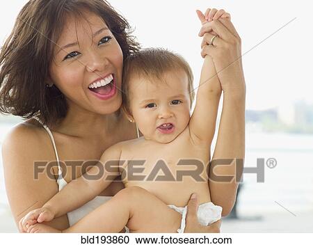 Stock Image - Smiling mother holding daughter. Fotosearch