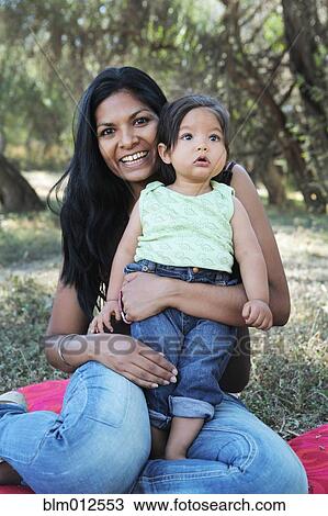 Smiling mother sitting on ground holding baby View Large Photo Image Stock Image - Smiling mother sitting on ground holding baby . Fotosearch