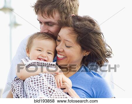 Stock Photo - Smiling parents holding daughter. Fotosearch