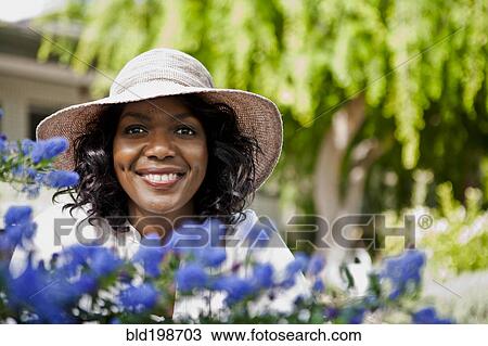 Stock Image - Smiling woman in garden. Fotosearch