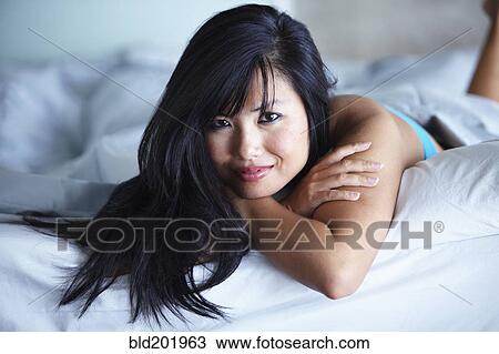 Stock Image - Smiling woman laying in bed. Fotosearch