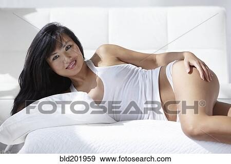 Stock Photo - Smiling woman laying on bed. Fotosearch