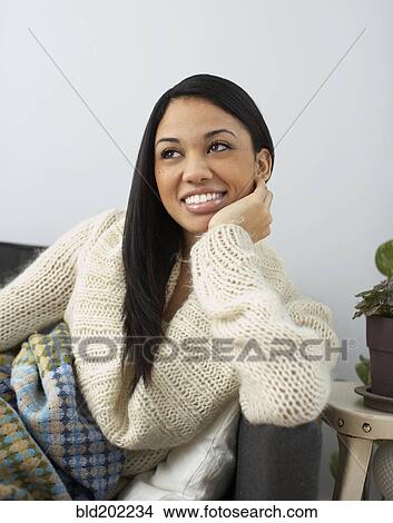 Picture - Smiling woman sitting on sofa. Fotosearch