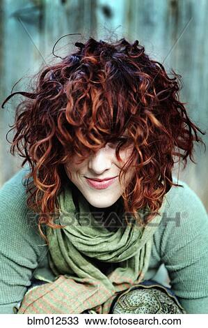 Stock Image - Smiling woman with curly red hair. Fotosearch