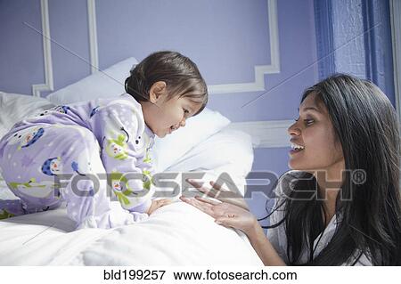Sri Lankan mother taking baby girl off bed View Large Photo Image Stock Photo - Sri Lankan mother taking baby girl off bed. Fotosearch