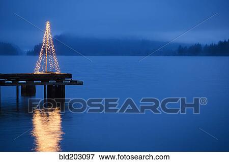 Stock Photo - String of lights in tree shape on wooden pier. Fotosearch